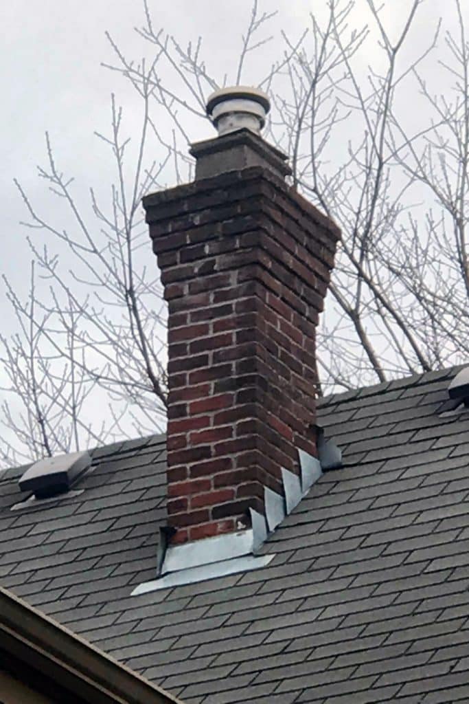 Brick chimney with flared top.
